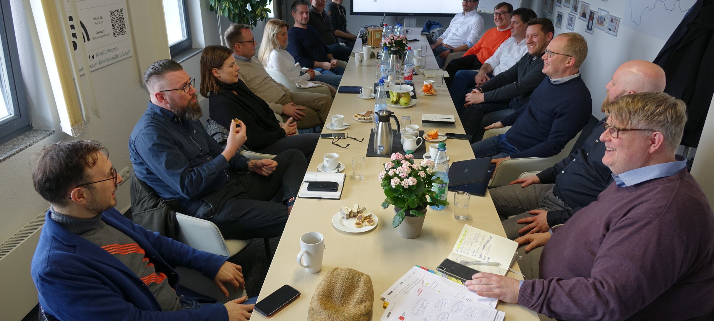 Menschen sitzen an Konferenztisch, an Fernsehr ist das mittelhessen.digital Logo | © Regionalmanagement Mittelhessen